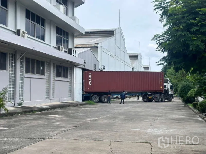 คลังสินค้า ให้เช่าในMueang Samut Prakan, Samut Prakan - รถบรรทุกตู้คอนเทนเนอร์เทียบท่าหน้าโกดัง ทางวิ่งกว้างมีแนวต้นไม้ สมุทรปราการ