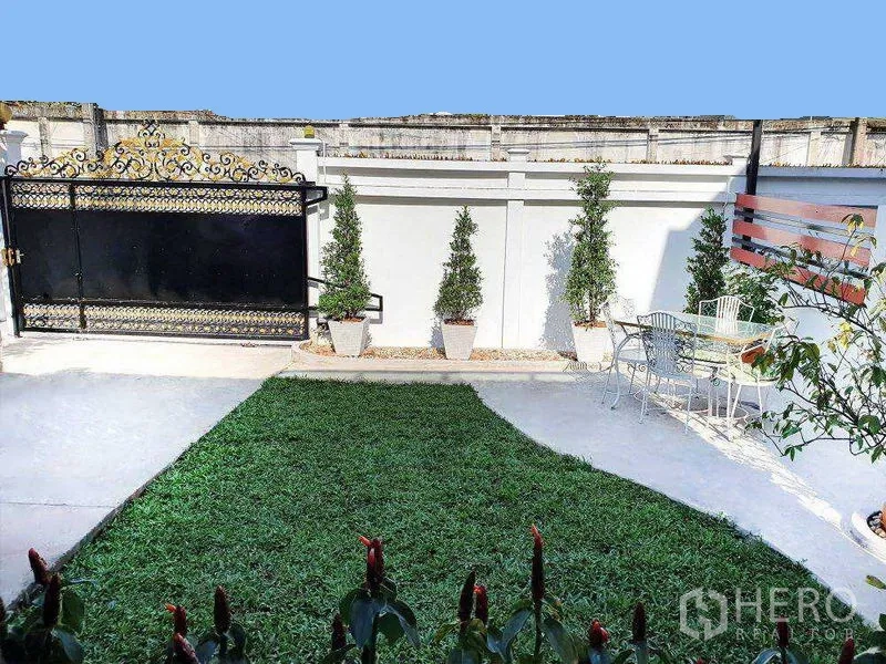 独立式住宅 出租在Phra Khanong, Bangkok - 私家庭院草坪，小乔木与户外休闲桌椅及装饰铁门。