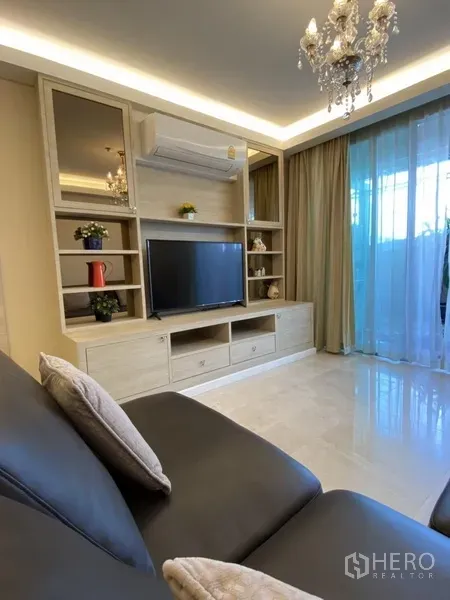 คอนโด ให้เช่าในBang Rak, Bangkok - ห้องนั่งเล่นสว่างพร้อมชั้นทีวีบิวท์อิน โคมระย้า และประตูกระจกออกระเบียง