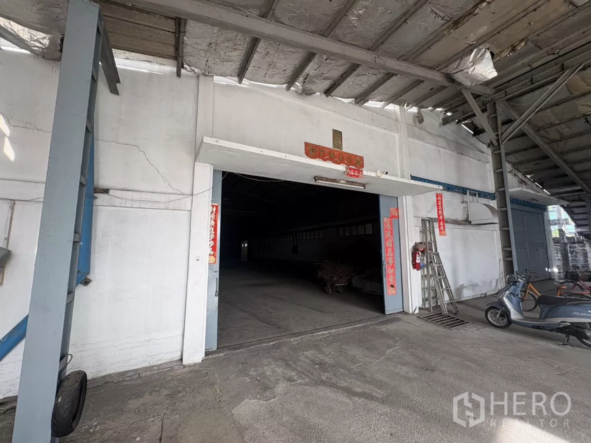 Warehouse for rent in Khlong Toei, Bangkok - Covered loading entrance of an older warehouse with a wide doorway and parked scooters.