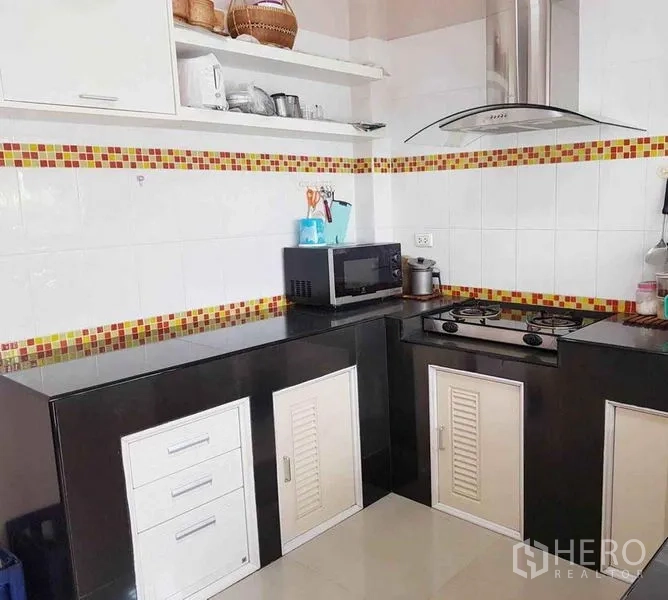 Detached House for sale in Nonthaburi - Kitchen corner with built-in cabinets, microwave, gas cooktop and hood.