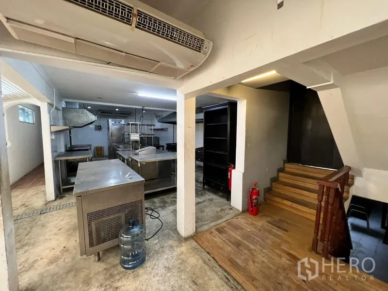 零售空间 出租在Bangkok - 后勤准备区，不锈钢操作台、楼梯与空调设备。