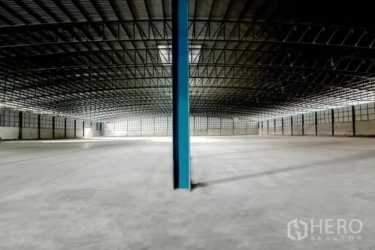 Warehouse for rent in Pathum Thani - Open-plan warehouse space with a central blue column and perimeter ventilation blocks.