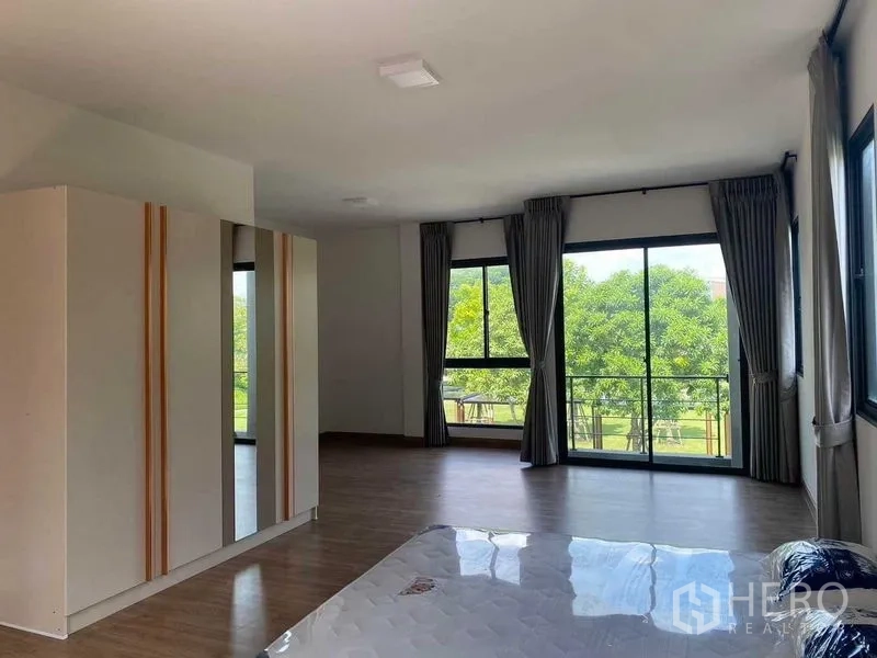 独立式住宅 出租在Khan Na Yao, Bangkok - 主卧宽敞，木地板、衣柜和面向公园的宽窗。