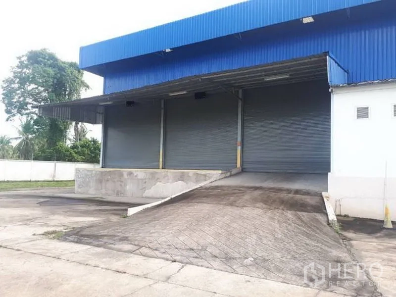 Warehouse for rent in Si Racha, Chon Buri - Warehouse exterior in Si Racha with covered loading dock, ramp, and three roller shutter doors.