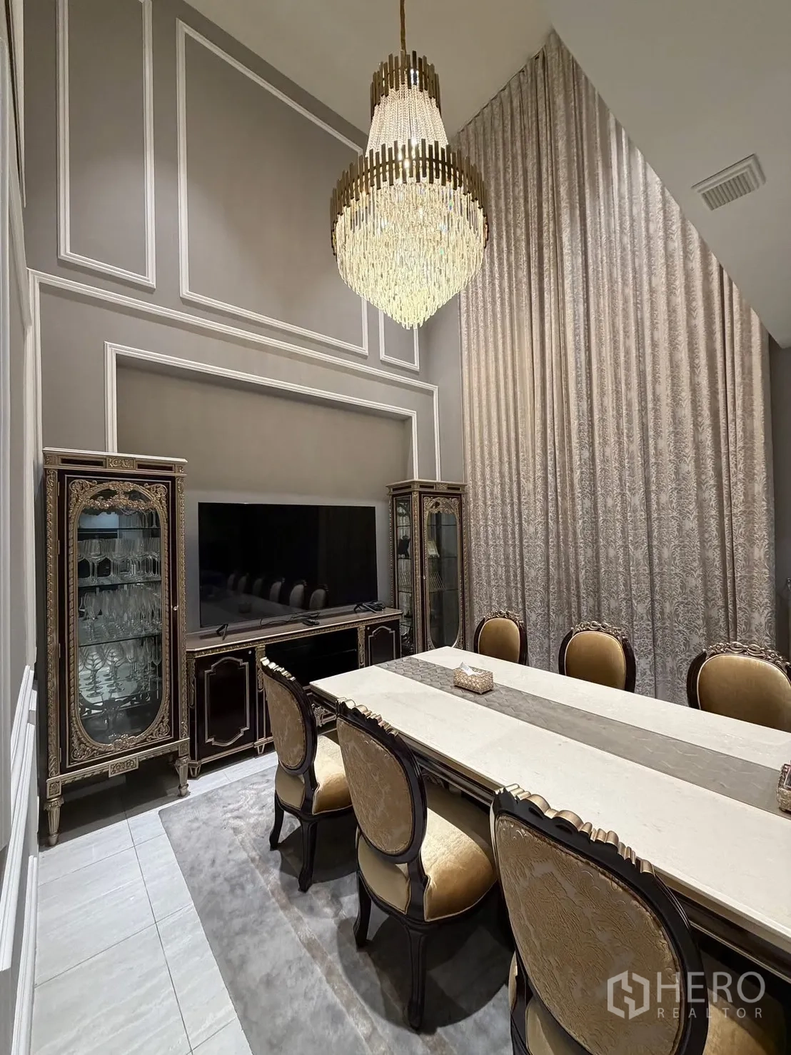 Detached House for rent or sale in Lak Si, Bangkok - Formal dining room with chandelier, display cabinets, and a large TV console.