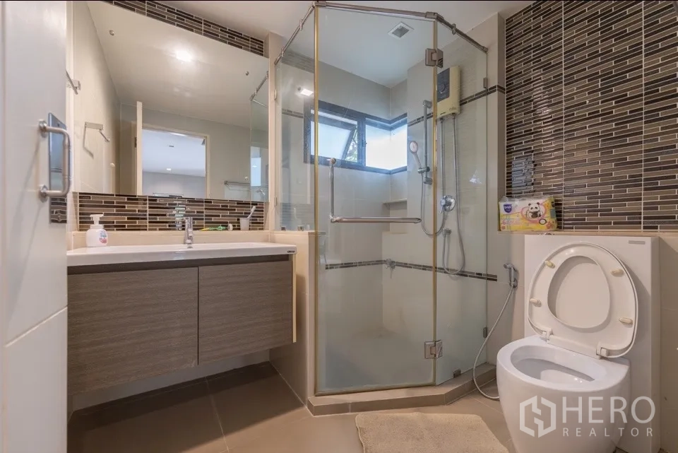 Detached House for rent or sale in Bang Kapi, Bangkok - Modern bathroom with glass-enclosed shower, vanity, and toilet.