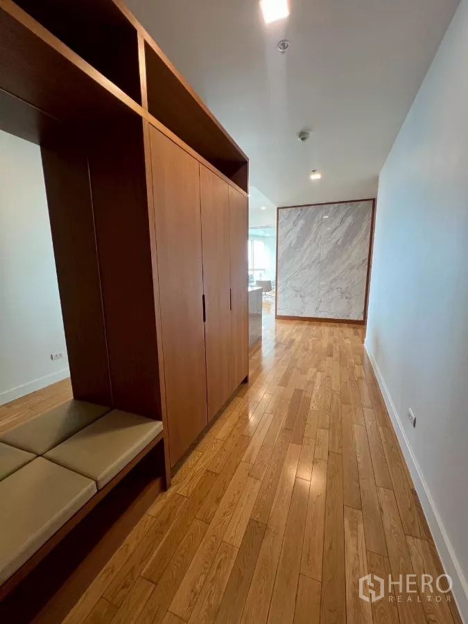 公寓 出租在Khlong Toei, Bangkok - 走廊设木质嵌入式衣柜与换鞋长凳，尽头为大理石装饰墙。