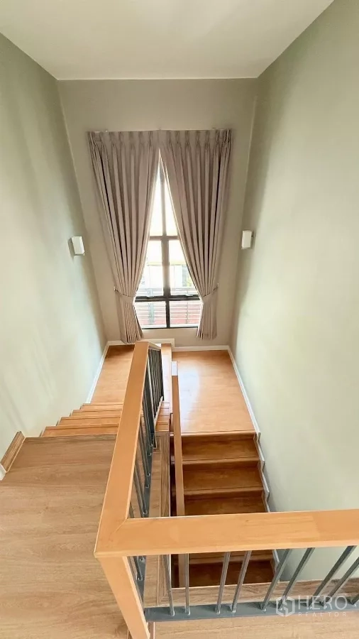 独立式住宅 出租或出售在Bang Phli, Samut Prakan - 木质楼梯配高窗，自然光洒入楼梯间。