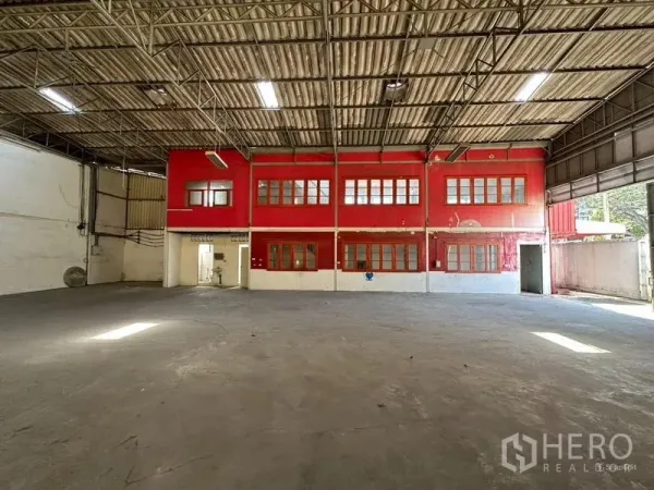 Warehouse for rent in Suan Luang, Bangkok - Clear-span warehouse hall with high metal roof and a red two-storey internal office block.