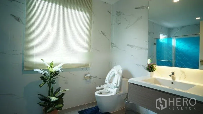 Detached House for rent or sale in Bang Phli, Samut Prakan - Bright bathroom with marble-look tiles, vanity and glass shower enclosure.