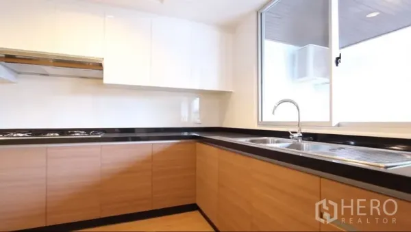 อพาร์ทเมนท์ ให้เช่าในKhlong Toei, Bangkok - ครัวรูปตัว U ตู้ไม้ เคาน์เตอร์สีดำ และหน้าต่าง ในอพาร์ตเมนต์เขตวัฒนา