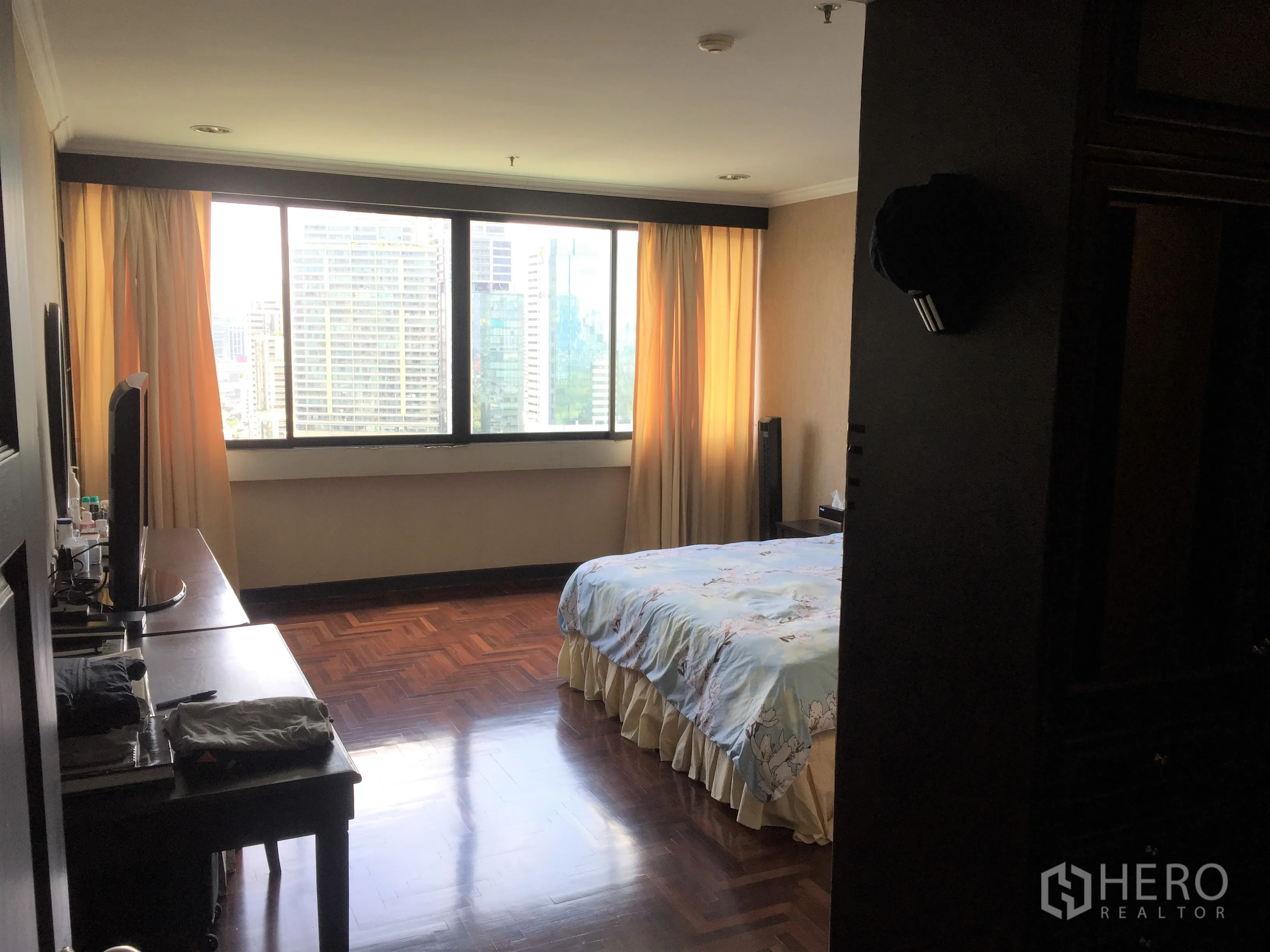 Condominium for rent or sale in Khlong Toei, Bangkok - Master bedroom with wide city-view window and wood floors in a Khlong Toei condo.