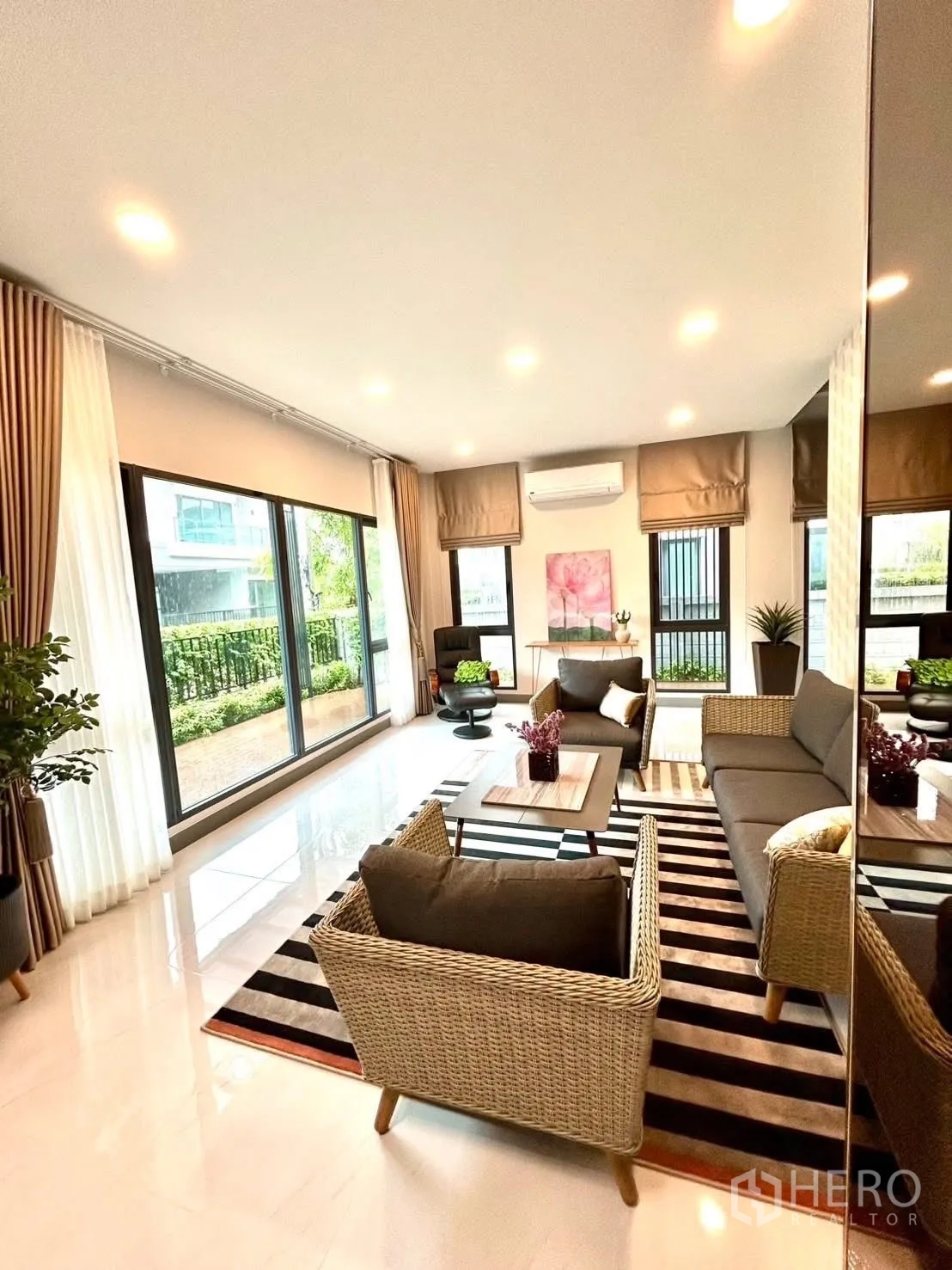 独栋房屋 for rent in Bang Phli, Samut Prakan - 采光充足的起居室，藤编沙发、条纹地毯与花园景观。