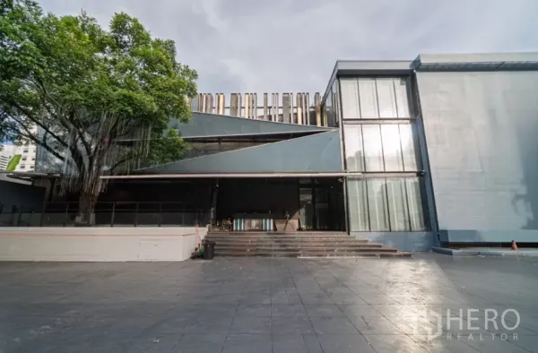 独立商业地产 出租在Watthana, Bangkok - 独栋场地正门，宽阶梯、大树以及落地玻璃立面。