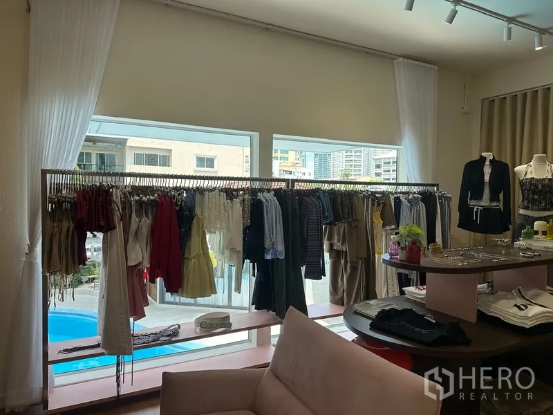 Retail Space for rent in Khlong Toei, Bangkok - Large windows with pool view behind clothing racks and a low pink display shelf.