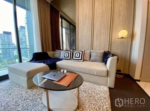 Condominium for rent in Watthana, Bangkok - Cozy living area with sofa, rug and round coffee table beside the balcony.
