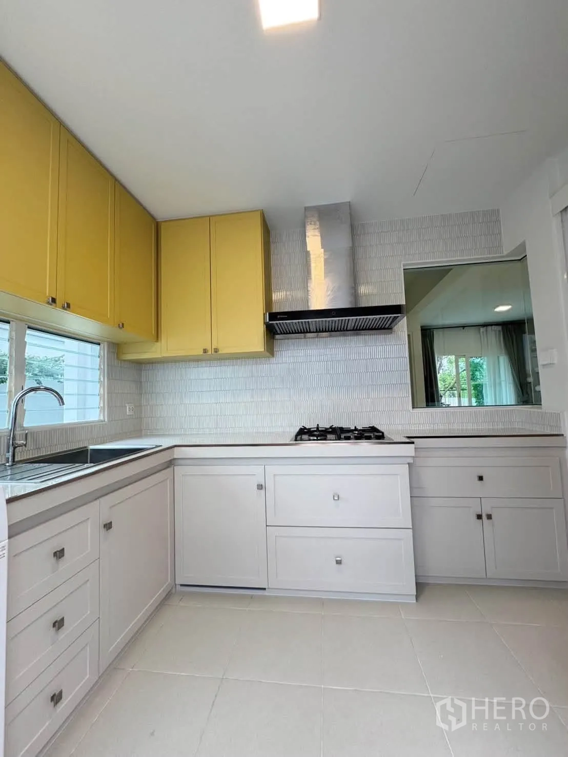 Detached House for rent in Bang Phli, Samut Prakan - Spacious L-shaped kitchen with yellow upper cabinets and white tiled floor.