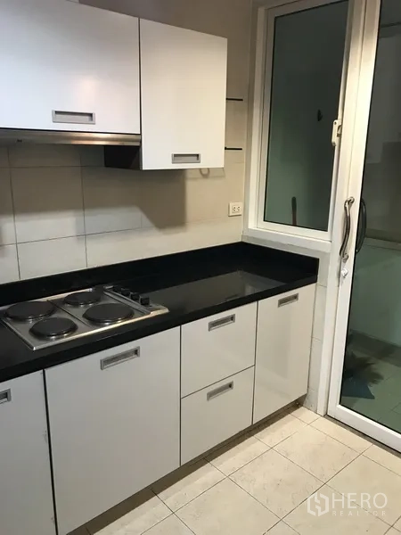 คอนโด ให้เช่าในKhlong Toei, Bangkok - ครัวแยกตู้สีขาว เคาน์เตอร์หินสีดำ และเตาไฟฟ้า