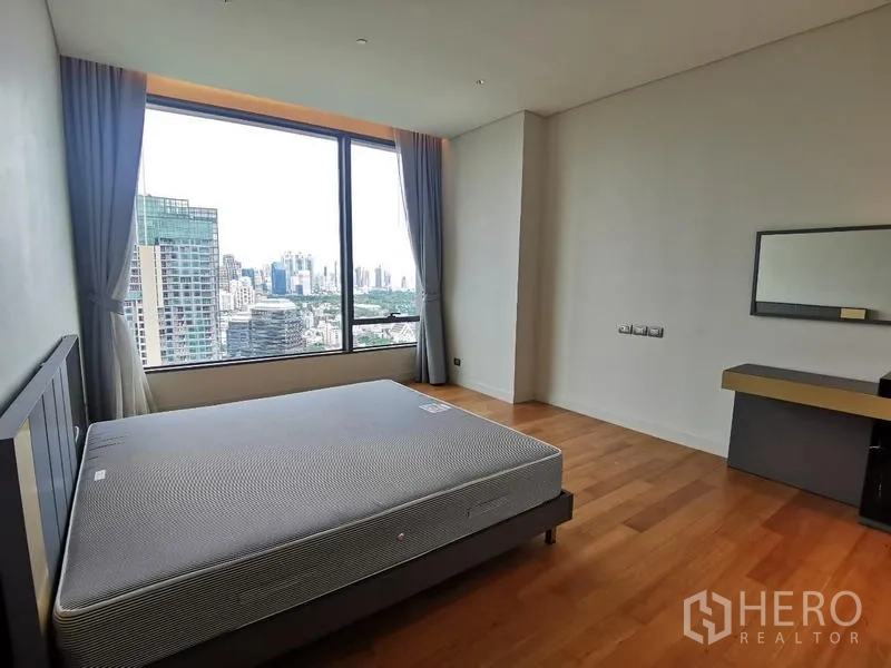 Condominium for rent in Pathum Wan, Bangkok - Corner bedroom with bed base, vanity and wide city-view window.