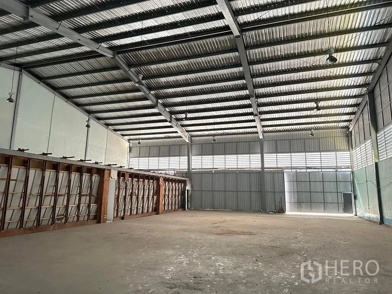 คลังสินค้า ให้เช่าในLam Luk Ka, Pathum Thani - ภายในโกดังเห็นโครงหลังคาเหล็ก ไฟส่องสว่าง และประตูบานเลื่อนขนาดใหญ่