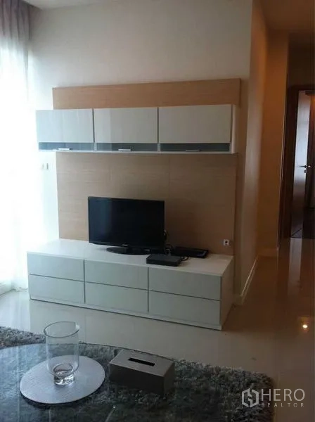 公寓 出售在Ratchathewi, Bangkok - 电视背景墙设吊柜与地柜，小型平板电视，窗边自然光。