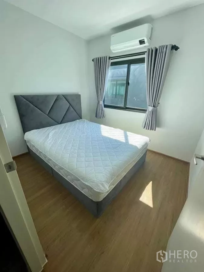 Townhouse for rent in Bang Phli, Samut Prakan - Sunlit bedroom with double bed, wood-look flooring, window and air conditioner.