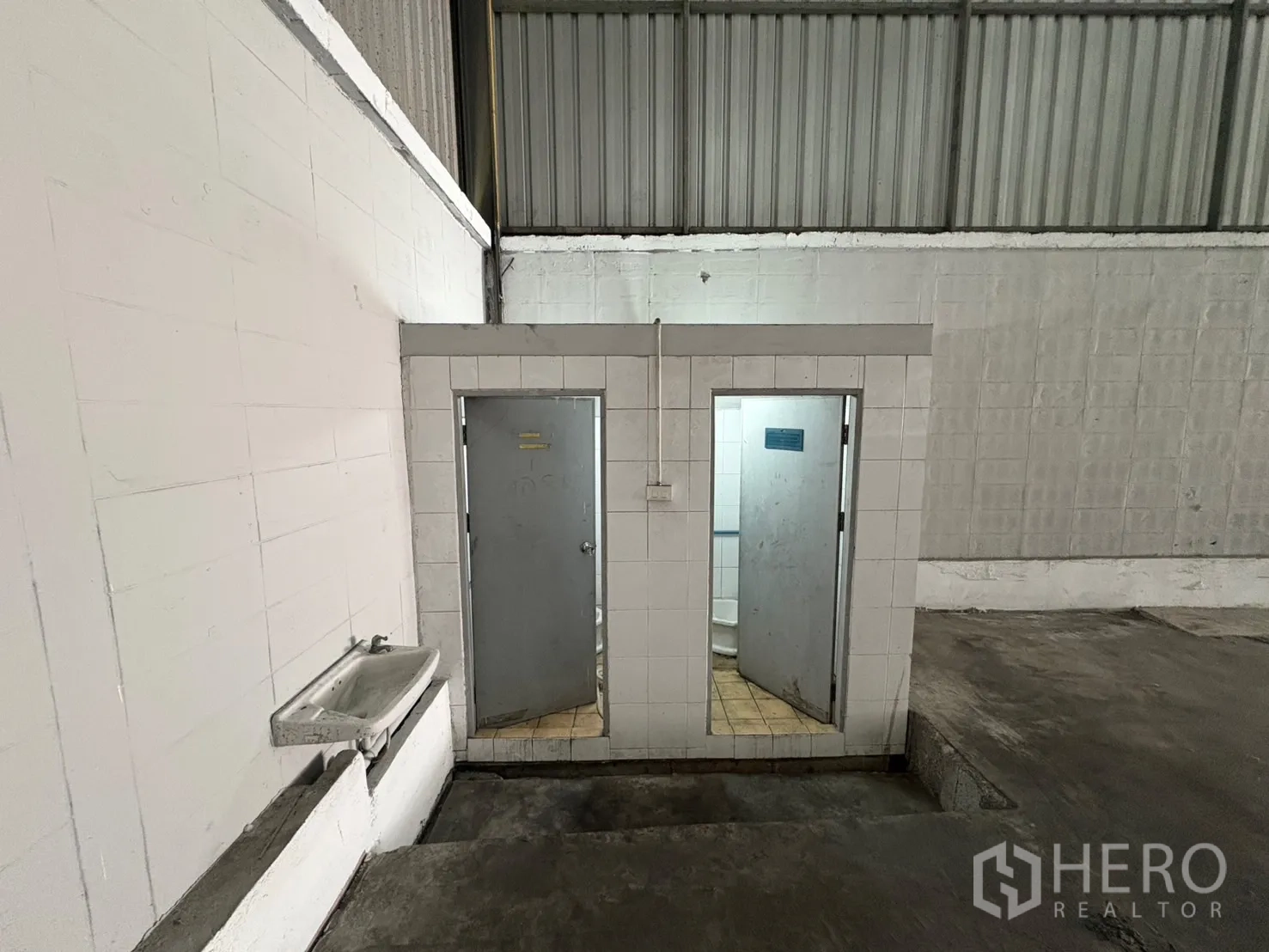 Warehouse for rent in Samut Prakan - Two internal restrooms with tiled walls and a utility sink inside the warehouse.