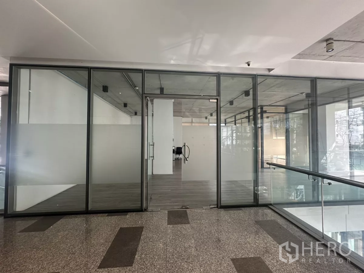 零售空间 出租 - 从室内连廊看到的店铺入口，整片玻璃立面与双扇门。