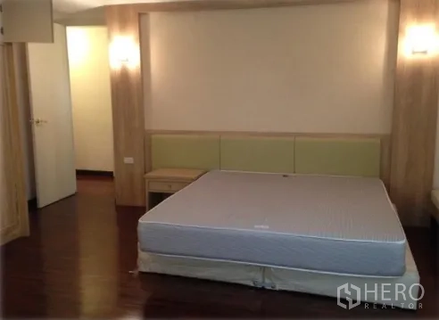 คอนโด ให้เช่าในWatthana, Bangkok - ห้องนอนมาสเตอร์ ผนังลายไม้ ไฟกิ่งข้างเตียง พื้นไม้ และเตียงคิงไซส์