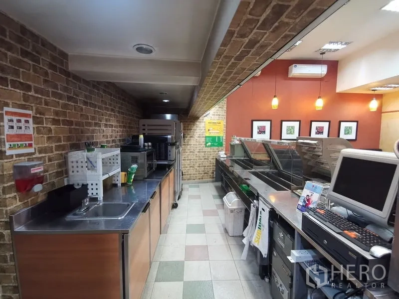 店屋 出租在Bangkok - 商用备餐区，砖纹墙面、吊灯与不锈钢操作台。