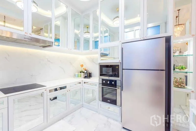 联排别墅 出租在Lat Phrao, Bangkok - 白色U型厨房，大理石饰面、镜面橱柜与不锈钢冰箱。