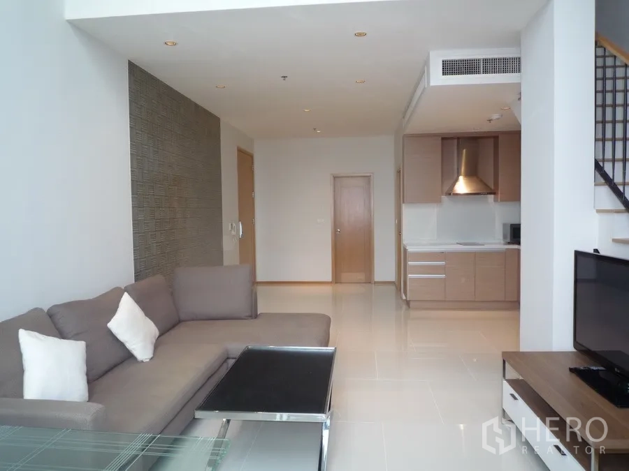 คอนโด ให้เช่าในKhlong Toei, Bangkok - ห้องนั่งเล่นคอนโดดูเพล็กซ์พร้อมโซฟา ทีวี ครัวเปิด และบันได ในเขตคลองเตย กรุงเทพฯ