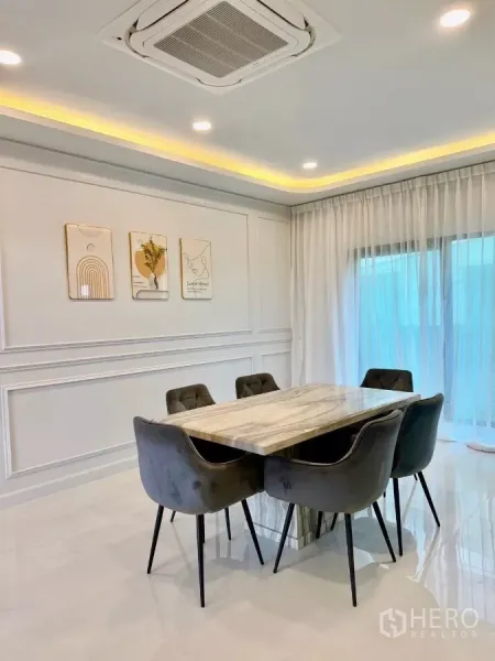 Detached House for rent in Bang Phli, Samut Prakan - Dining room with marble-top table for six, cassette ceiling air-conditioner and sheer curtains.