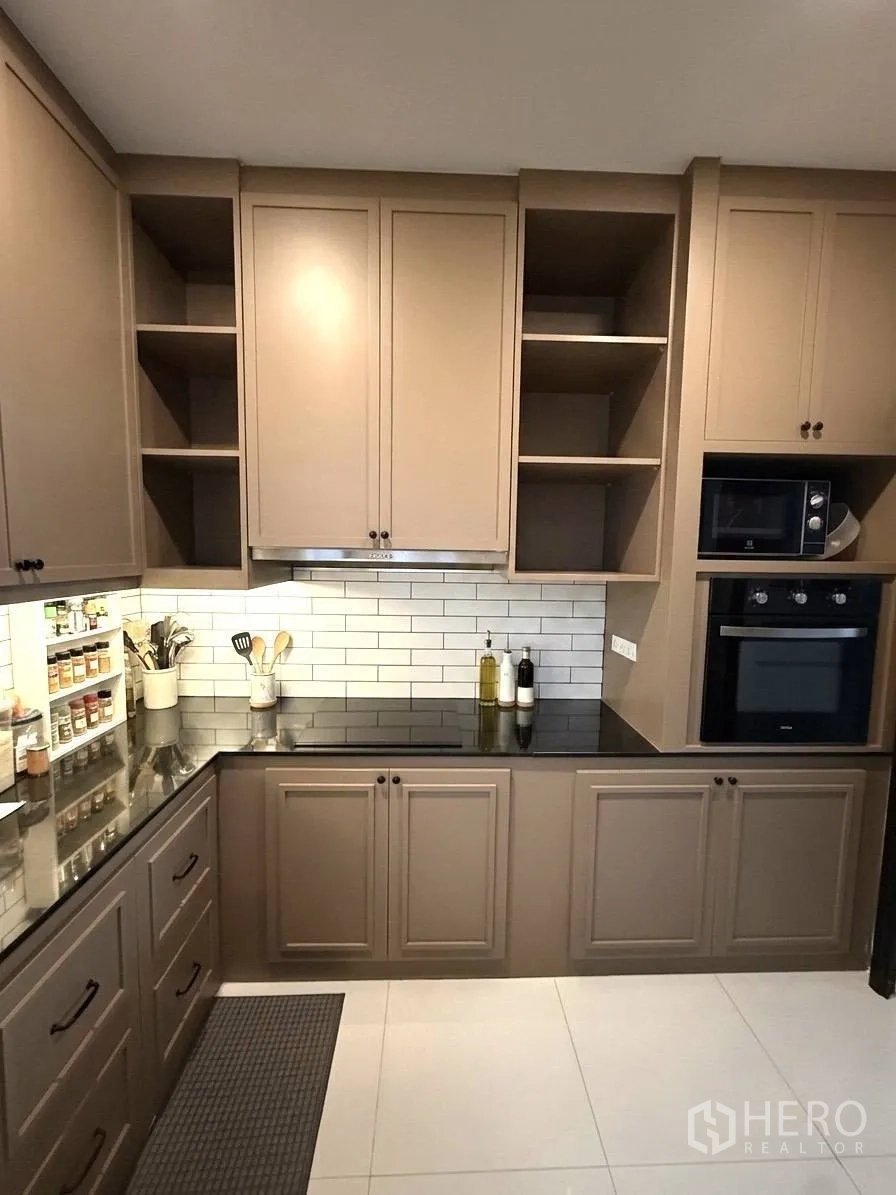 Detached House for rent in Wang Thonglang, Bangkok - Fitted kitchen with shaker-style cabinets, black countertops, and built-in oven.