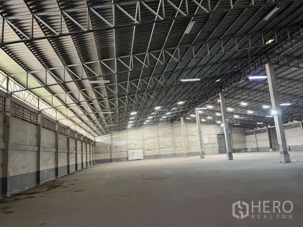 Warehouse for rent - Vast warehouse interior with clear-span truss ceiling, bright lighting and smooth concrete floor.