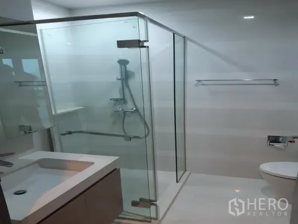 Condominium for rent in Khlong Toei, Bangkok - Bright bathroom with glass-enclosed shower and vanity.