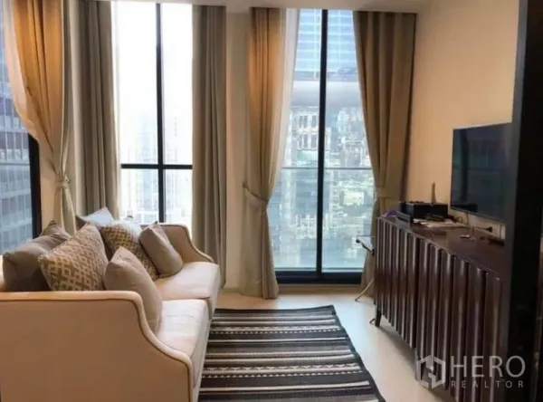 คอนโด ให้เช่าในPathum Wan, Bangkok - ห้องนั่งเล่นสว่างด้วยหน้าต่างบานใหญ่ ประตูระเบียง โซฟา และตู้วางทีวี มองเห็นวิวสกายไลน์