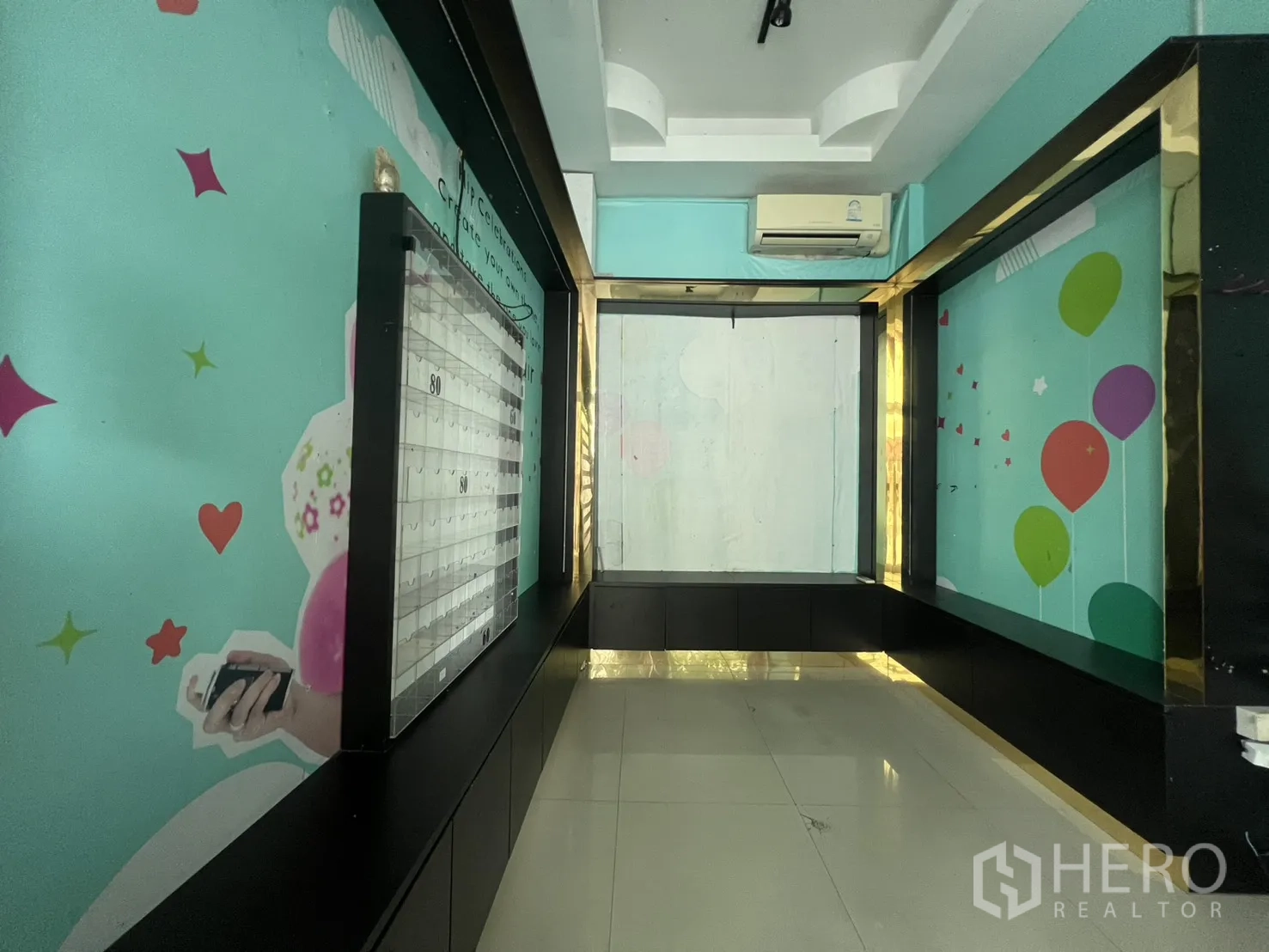零售空间 for rent in Watthana, Bangkok - 狭长展示区，青绿色主题墙与黑色展示框，挂壁空调与地砖。