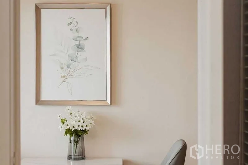 Condominium for rent - Framed botanical artwork above a small table with a vase of white flowers.