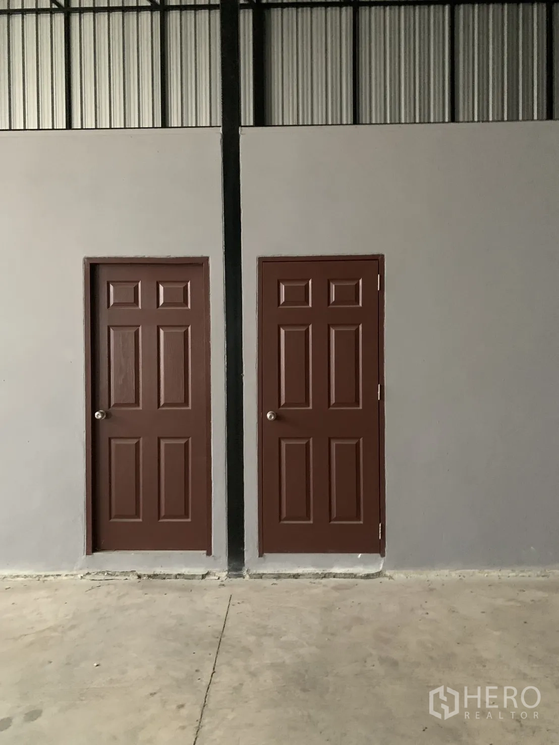 Warehouse for sale in Bang Len, Nakhon Pathom - Two brown interior doors on a grey wall inside the warehouse, likely restroom or storage.