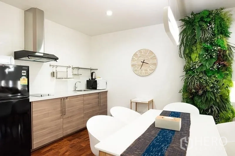 คอนโด ให้เช่าในPathum Wan, Bangkok - ครัวบิลท์อินตู้ไม้ เครื่องดูดควัน โต๊ะทานข้าว และผนังสวนแนวตั้งสีเขียว