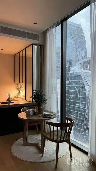 公寓 出租在Pathum Wan, Bangkok - 落地窗旁的用餐角与紧凑厨房，俯瞰城市摩天楼景观