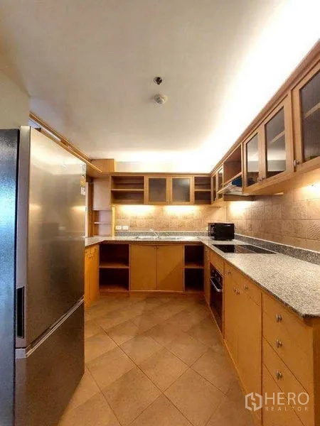 อพาร์ทเมนท์ ให้เช่า - ครัวรูปตัว U ท็อปหินแกรนิต ผนังไทล์ ตู้กระจกด้านบน และเตาไฟฟ้า