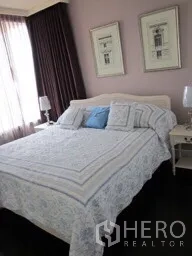 Condominium for rent in Khlong Toei, Bangkok - Cozy master bedroom with double bed, soft linens, bedside tables and framed artwork.