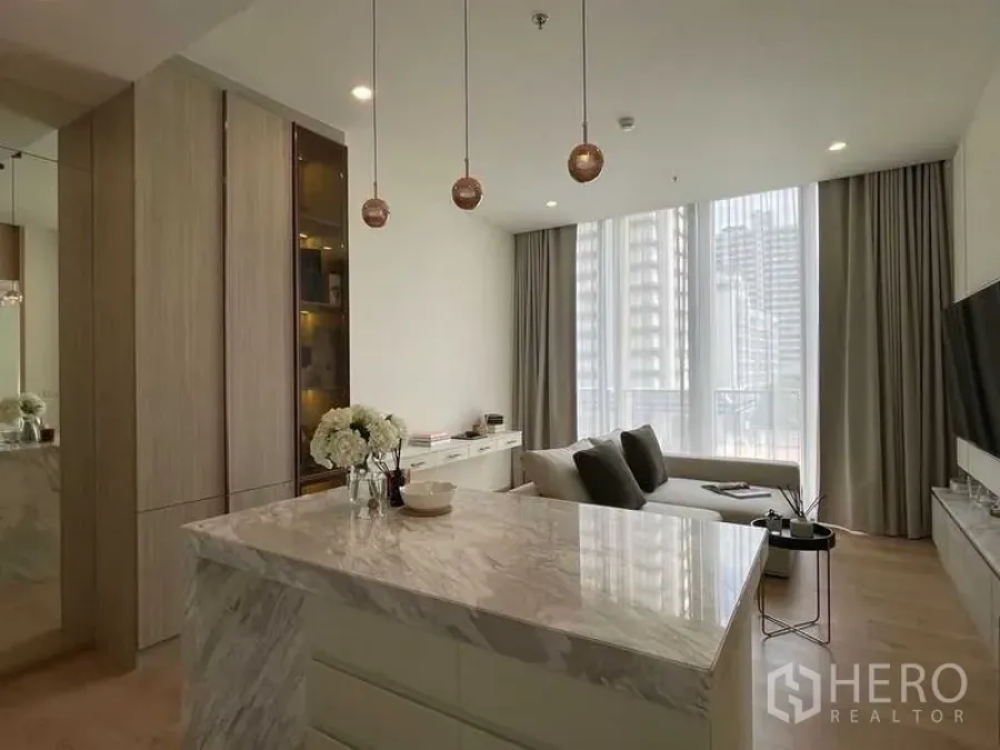 公寓 出售在Watthana, Bangkok - 抛光大理石中岛与铜色吊灯，面向明亮客厅和通高窗。