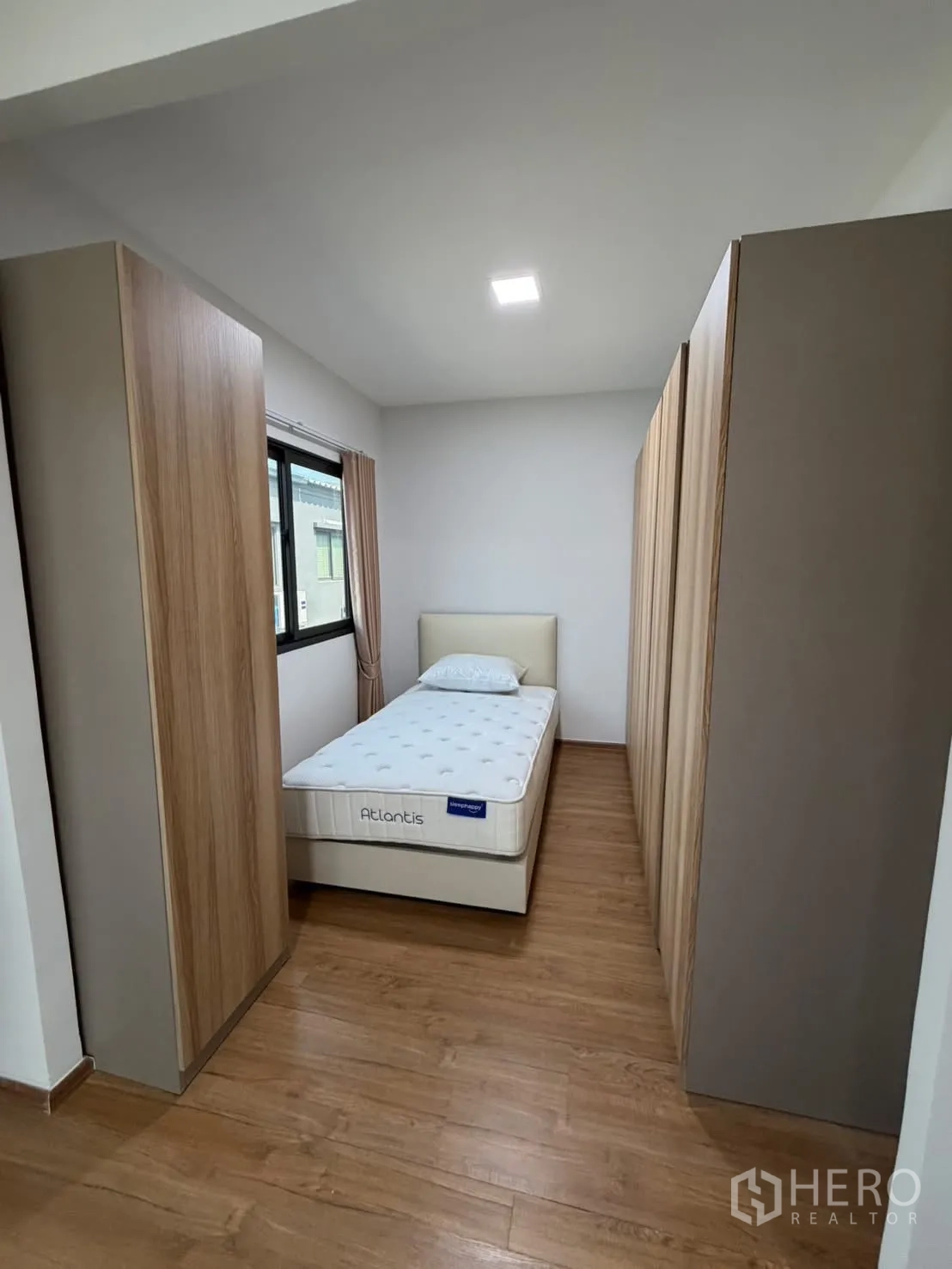 Townhouse for rent in Bang Phli, Samut Prakan - Cozy bedroom with a single bed flanked by wardrobes and warm wood flooring.