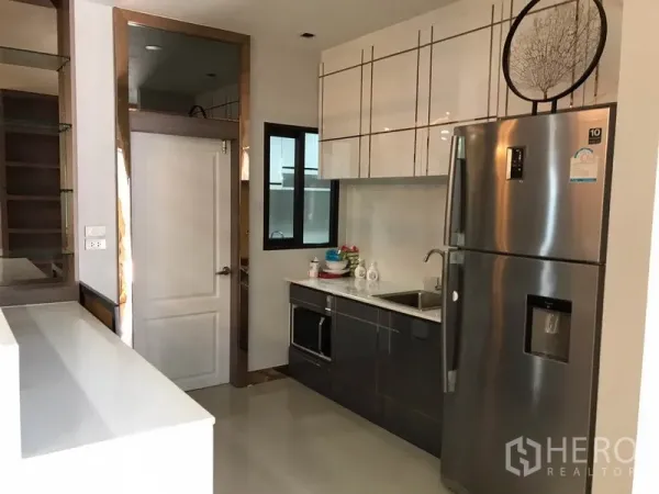 Detached House for rent in Bang Phli, Samut Prakan - Compact kitchen with glossy cabinets, sink, microwave and double-door fridge.