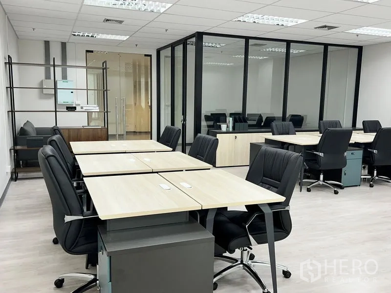 Office Space for rent in Sathon, Bangkok - Open-plan office with rows of desks and a glass-walled meeting room in the background.