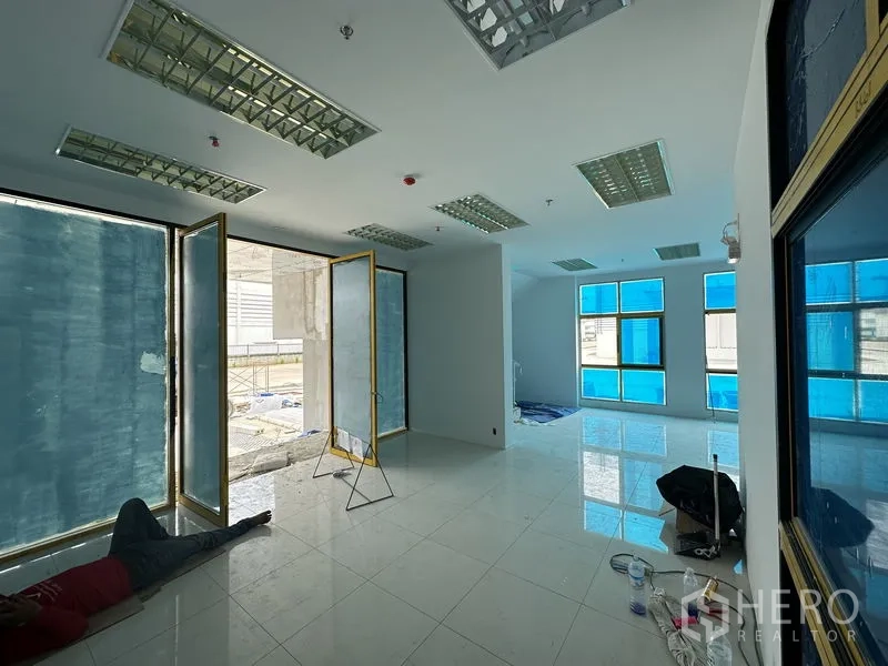 Factory for rent in Khlong Luang, Pathum Thani - Spacious office room with drop ceiling lights and blue-tinted windows under construction.